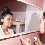 girl with moisturiser on nose in mirror reflection