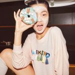 girl wearing glow mask and holding a donut in her face