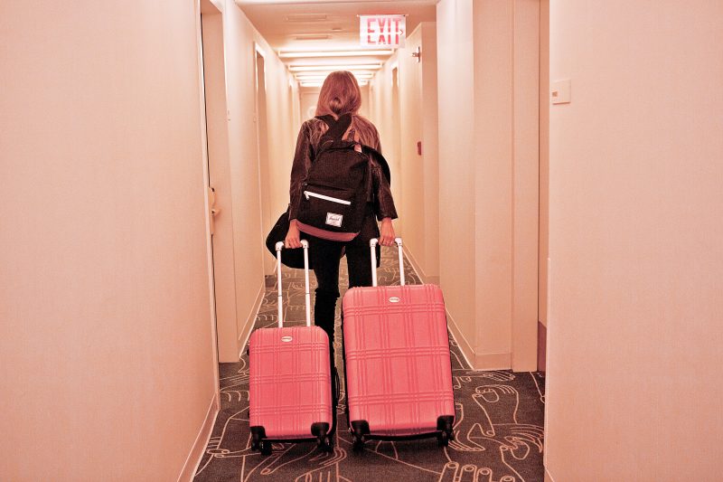 Frank Body’ babe wheeling her pink suitcase through hotel. She is about to use her travel skincare kit, The Grind high club. The mini travel satchel contains four coffee scrubs in four scents. 